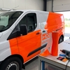 Échenillage d'un lettrage découpé dans du film adhésif fluorescent orange Oracal 6510 sur table d'atelier
